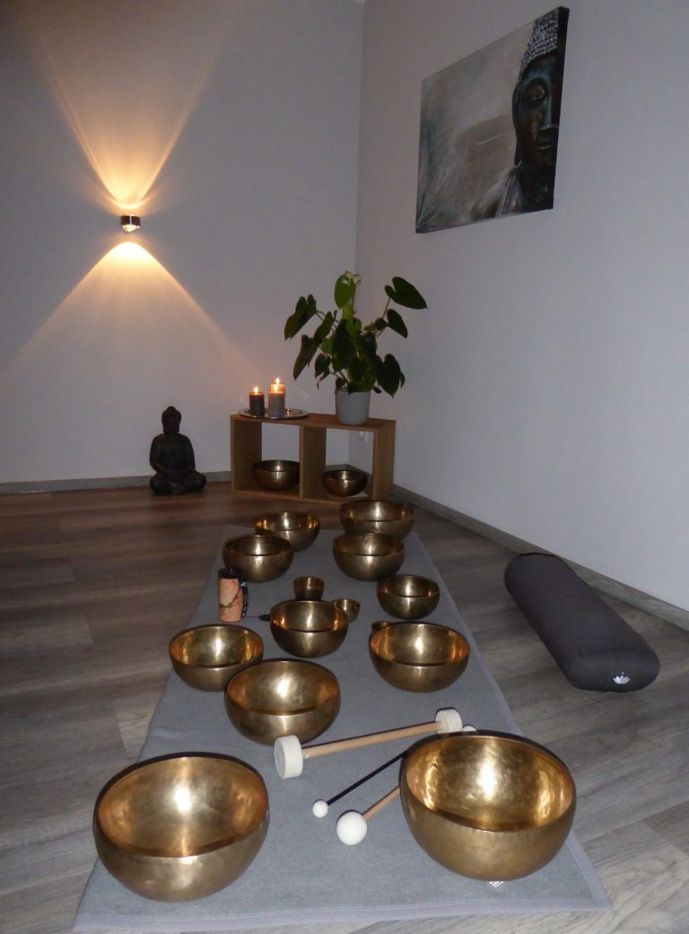 Ruhiger Raum mit Klangschalen, Buddha-Statuen und Pflanzen für Meditation.